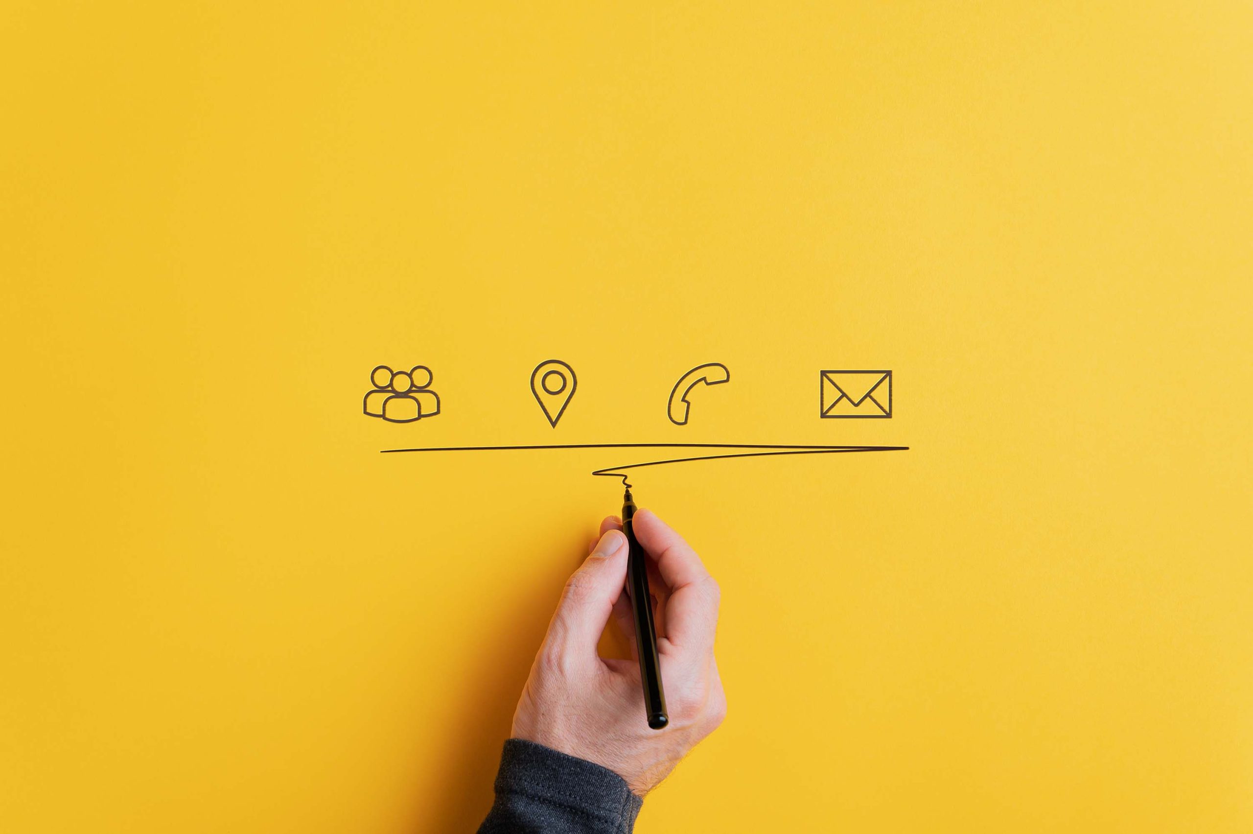 Male hand underlining hand drawn contact and communication icons on yellow background. With copy space.