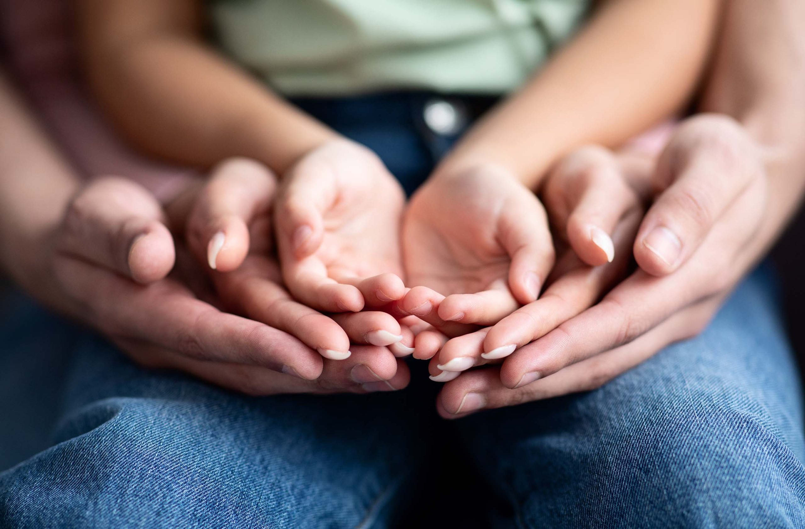 Parents and child placing their hands together, closeup shot. Conceptual image for family support, unity and love, selective focus at three pair of palms