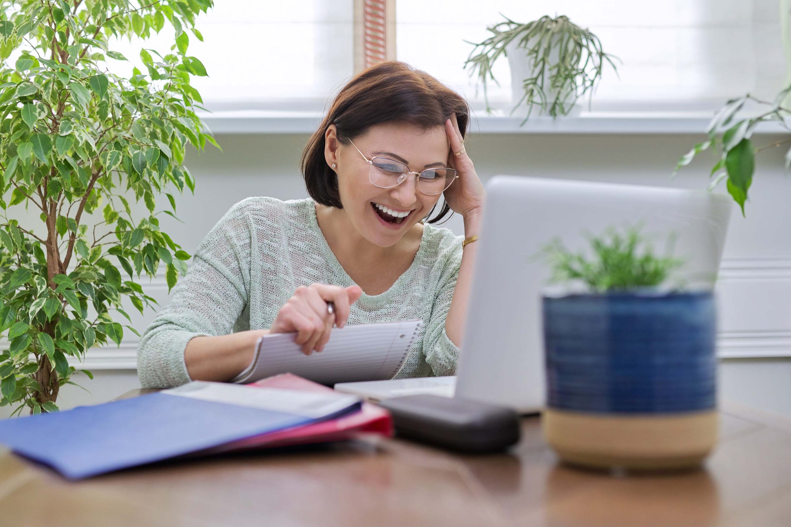 Female teacher teaching online, sitting at home at table with laptop Female teacher teaching online, sitting at home at table with laptop. Talking woman looking into computer webcam. E-education, online courses, distance learning, technologies in education